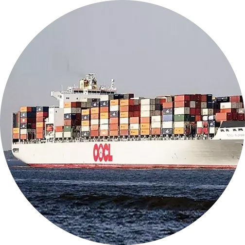 Large OOCL container ship carrying multicolored containers while sailing on the sea under a clear sky.