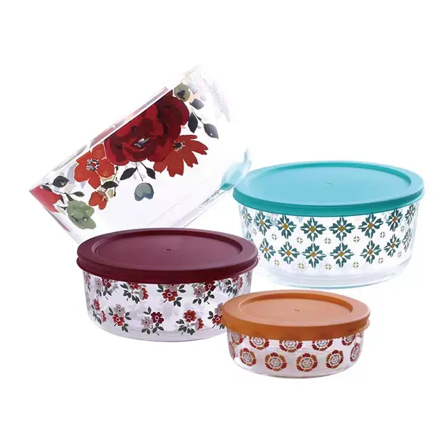 Four glass kitchen containers with colorful floral patterns and matching lids in blue, maroon, and orange.
