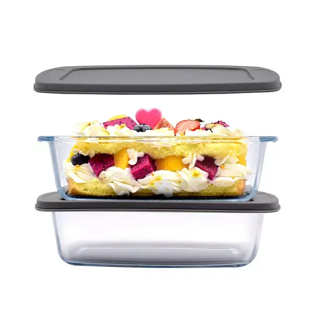 Glass kitchen container filled with a colorful fruit dessert topped with cream and a heart-shaped decoration, lid beside.
