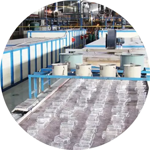 A production line at a factory showing rows of clear glass containers on a conveyor belt with machinery in the background.