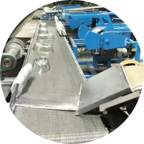 Glass containers on an industrial production line with blue machinery in a factory setting, showcasing kitchenware manufacturing.