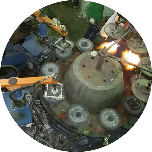 Industrial machinery with rotating molds and flames involved in glass production, highlighting the manufacturing process.