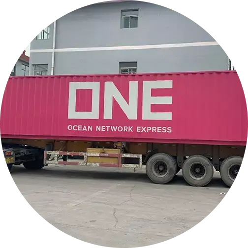 Pink Ocean Network Express shipping container mounted on a trailer with visible wheels in an industrial area.