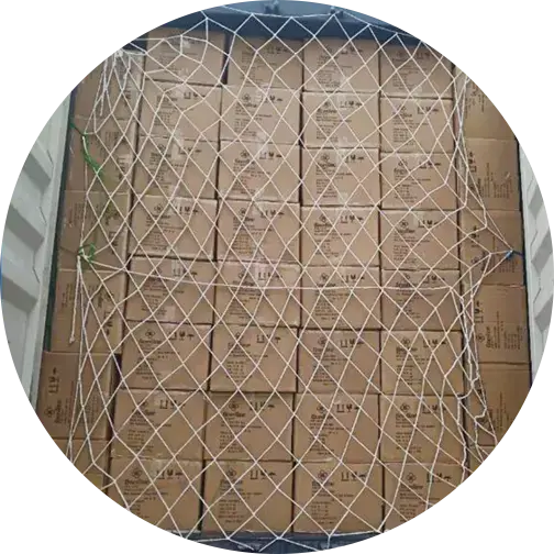 Stacks of cardboard boxes secured with netting in a storage container, likely for transportation or storage purposes.