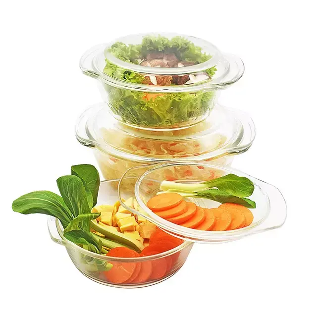 Three transparent glass containers stacked with fresh vegetables and salad. The top container holds a salad with greens and chunks of meat, middle has shredded vegetables, and the bottom shows sliced carrots, greens, and tofu.