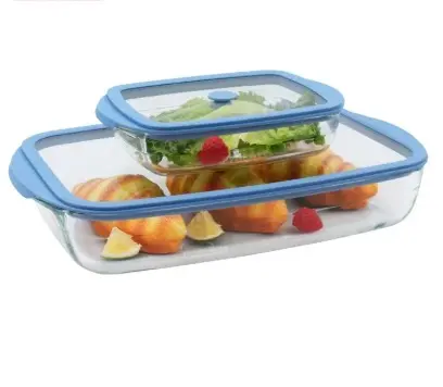 Two glass containers with blue lids, one smaller placed inside the larger, filled with sliced fruit and vegetables.
