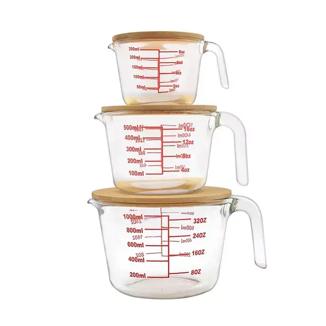 Three stacked glass measuring cups with red measurement markings and wooden lids, featuring integrated handles for easy pouring.