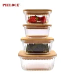 Four stacked glass kitchen containers with bamboo lids, the top containing strawberries and the third containing broccoli.