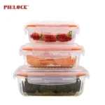 Three stacked glass food containers with orange lids, containing strawberries, chips, and broccoli.